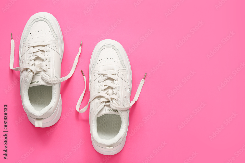 Stylish white sneakers on pink background