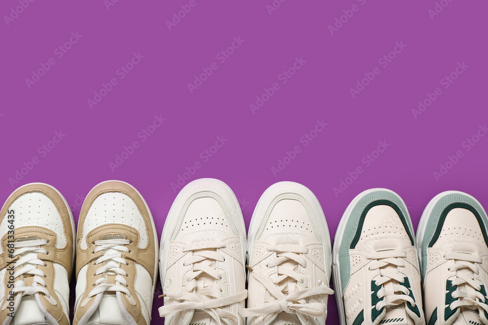 Different stylish sneakers on purple background