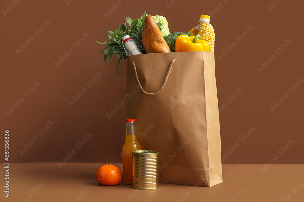 Paper shopping bag with different fresh products on brown background