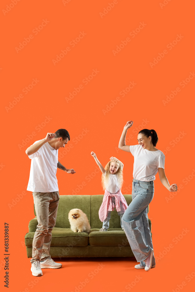 Happy family with sofa dancing on orange background