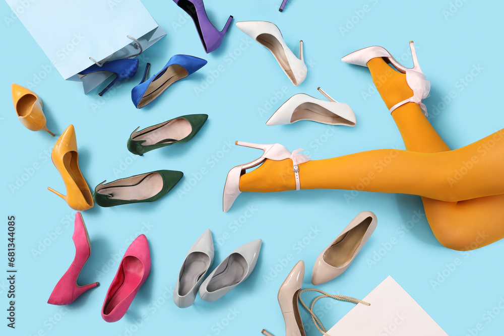 Woman with different high heeled shoes and shopping bags on color background