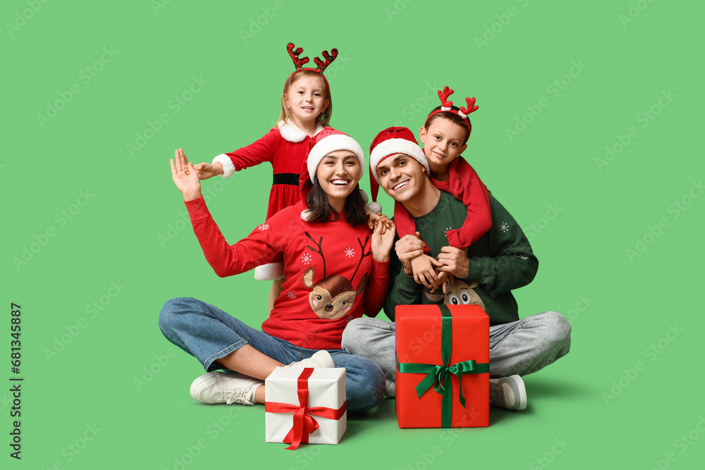 Happy family in Christmas clothes and gifts on green background