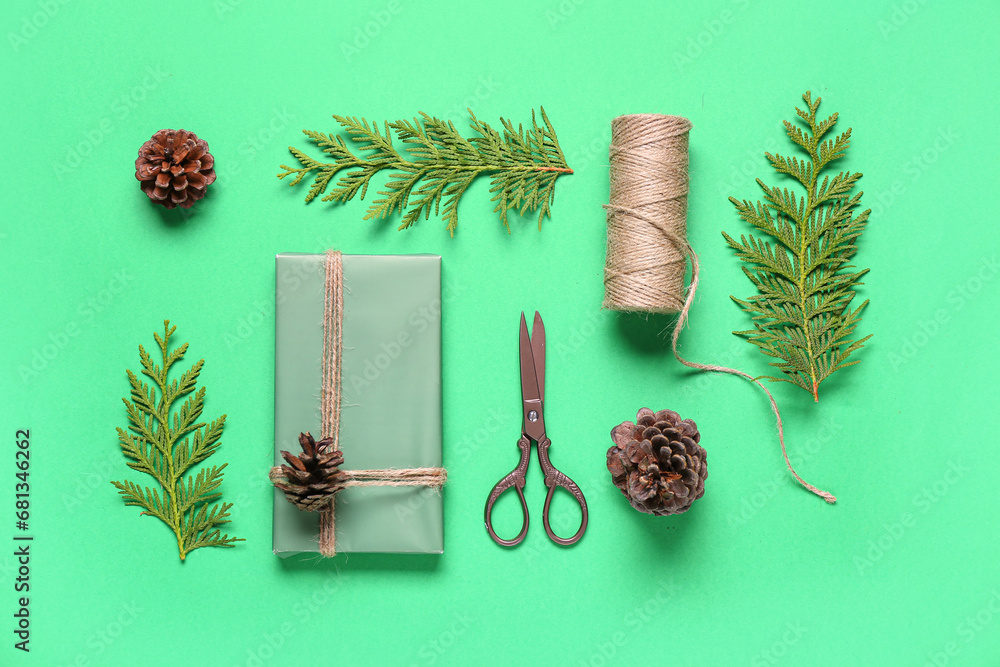 Pine cones with Christmas gift box and coniferous branches on green background