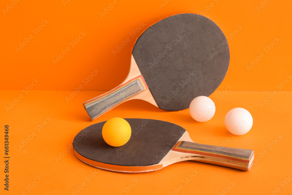 Ping pong rackets and balls on orange background