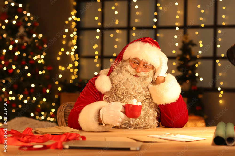 Thoughtful Santa Claus drinking hot chocolate with marshmallows at home on Christmas eve