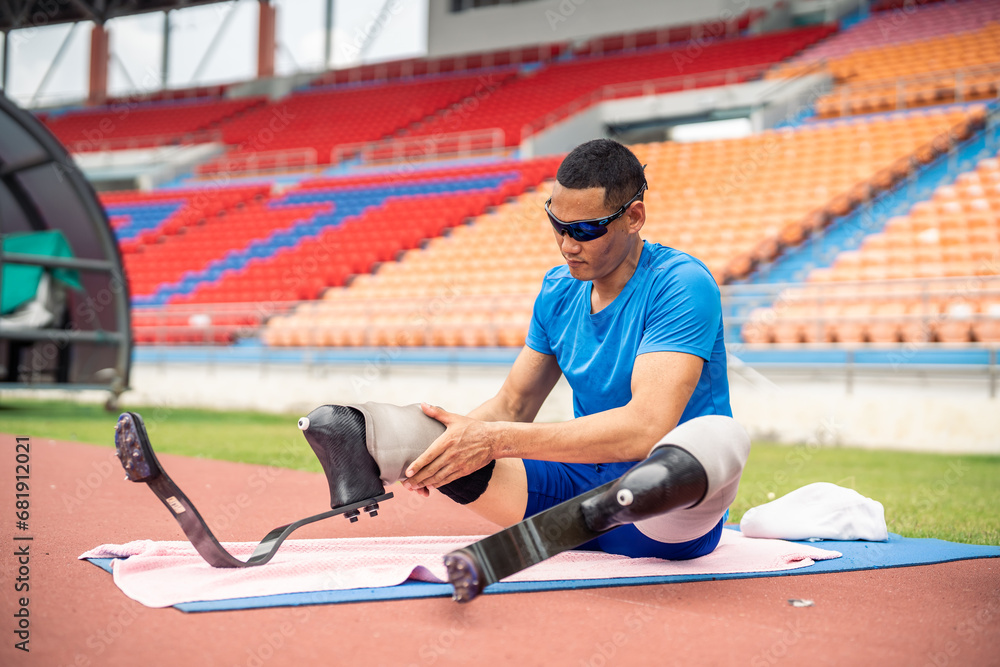 Asian para-athlete with prosthetic blades stretching leg in stadium. 