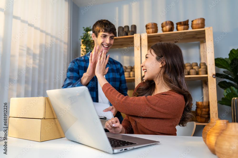 Attractive young couple packing vase goods order into box for customer. 