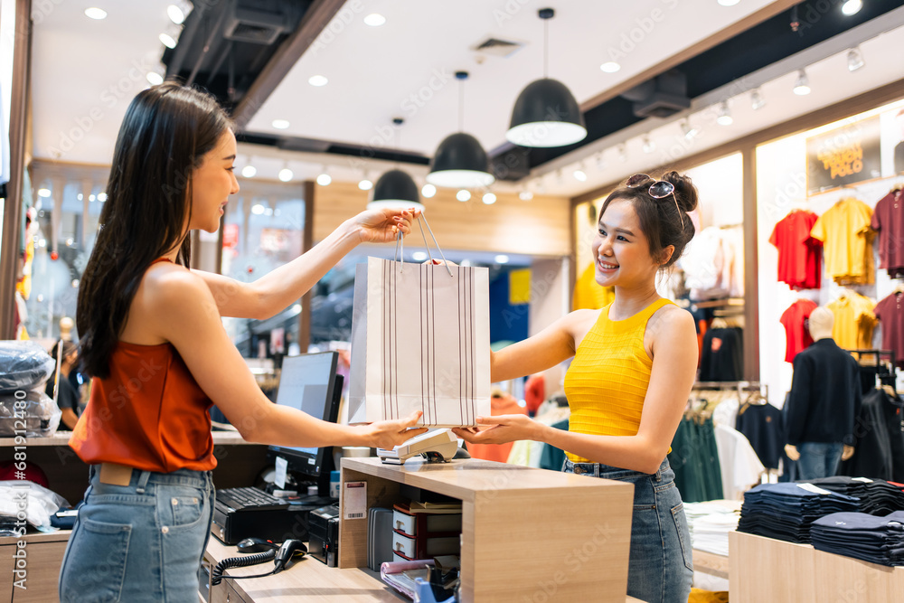 Asian young woman use credit card pay clothes product in shopping mall. 