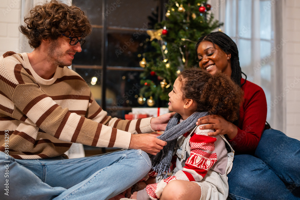 Caucasian father puts scarf on young daughter during Christmas time. 