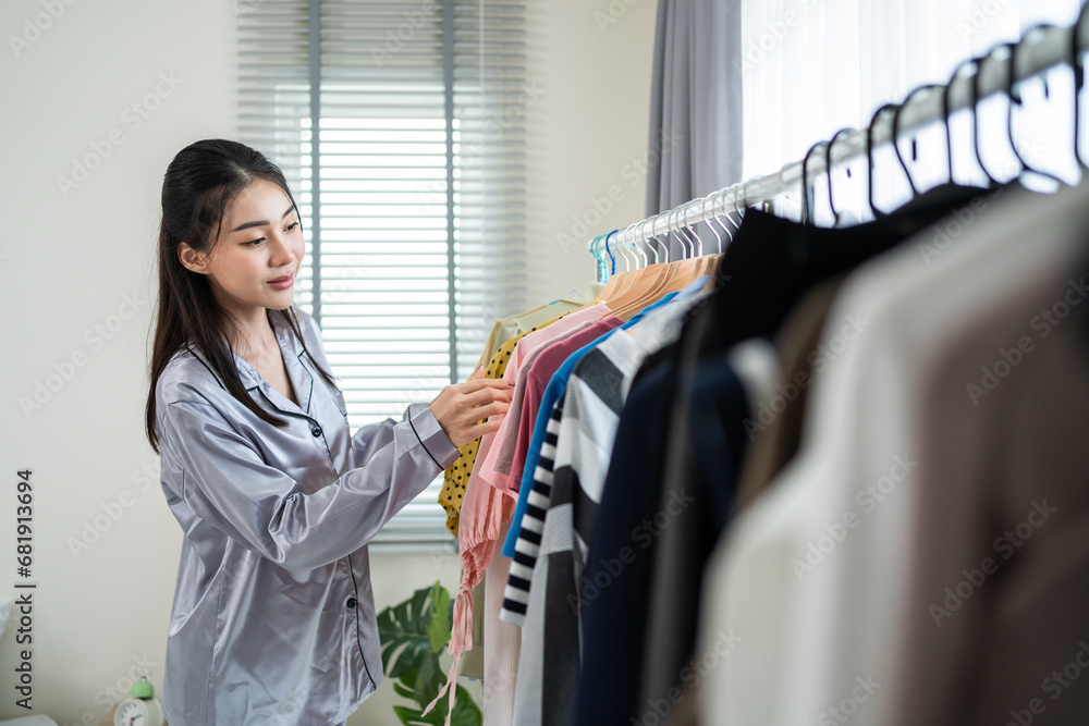 Asian beautiful young women  choosing clothes on closet rack at home. 