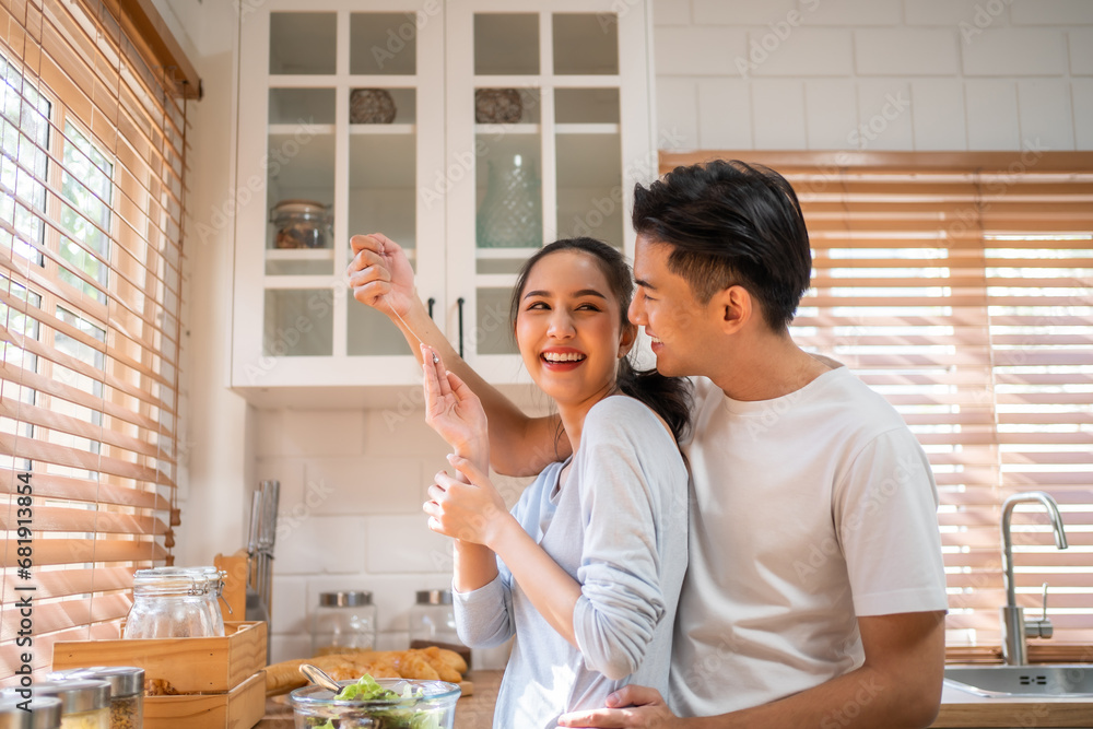 Asian romantic man making surprise girlfriend with necklace in kitchen. 