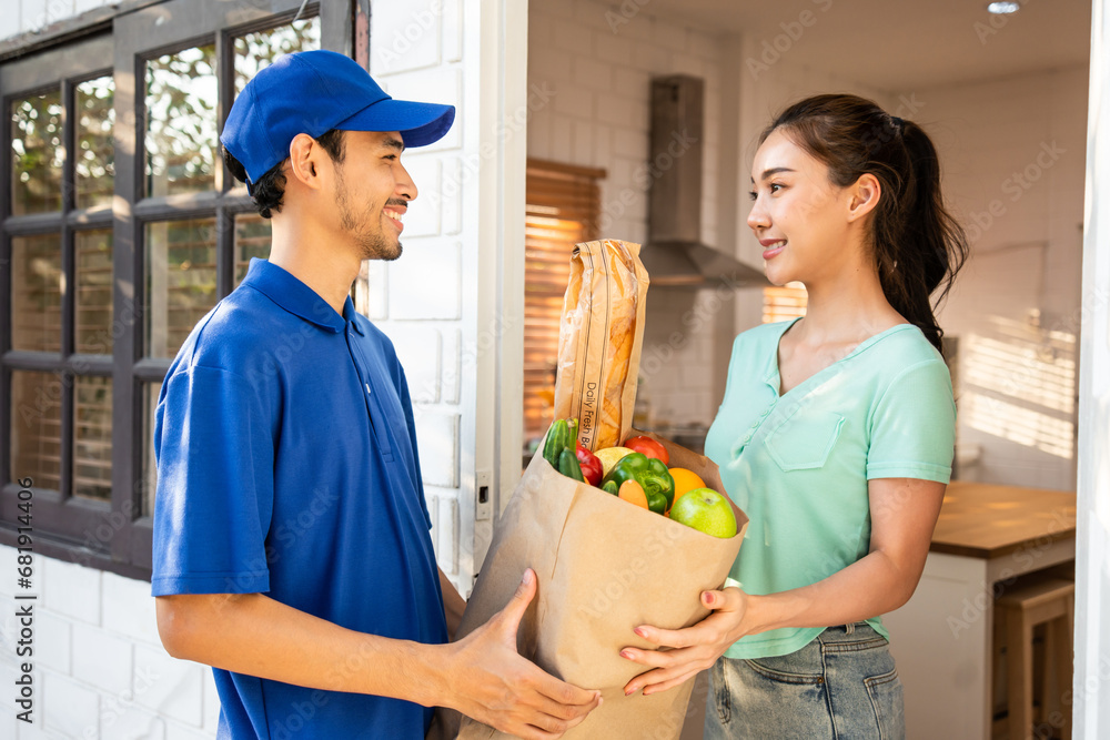 Asian young delivery man delivering package to female customer at home. 